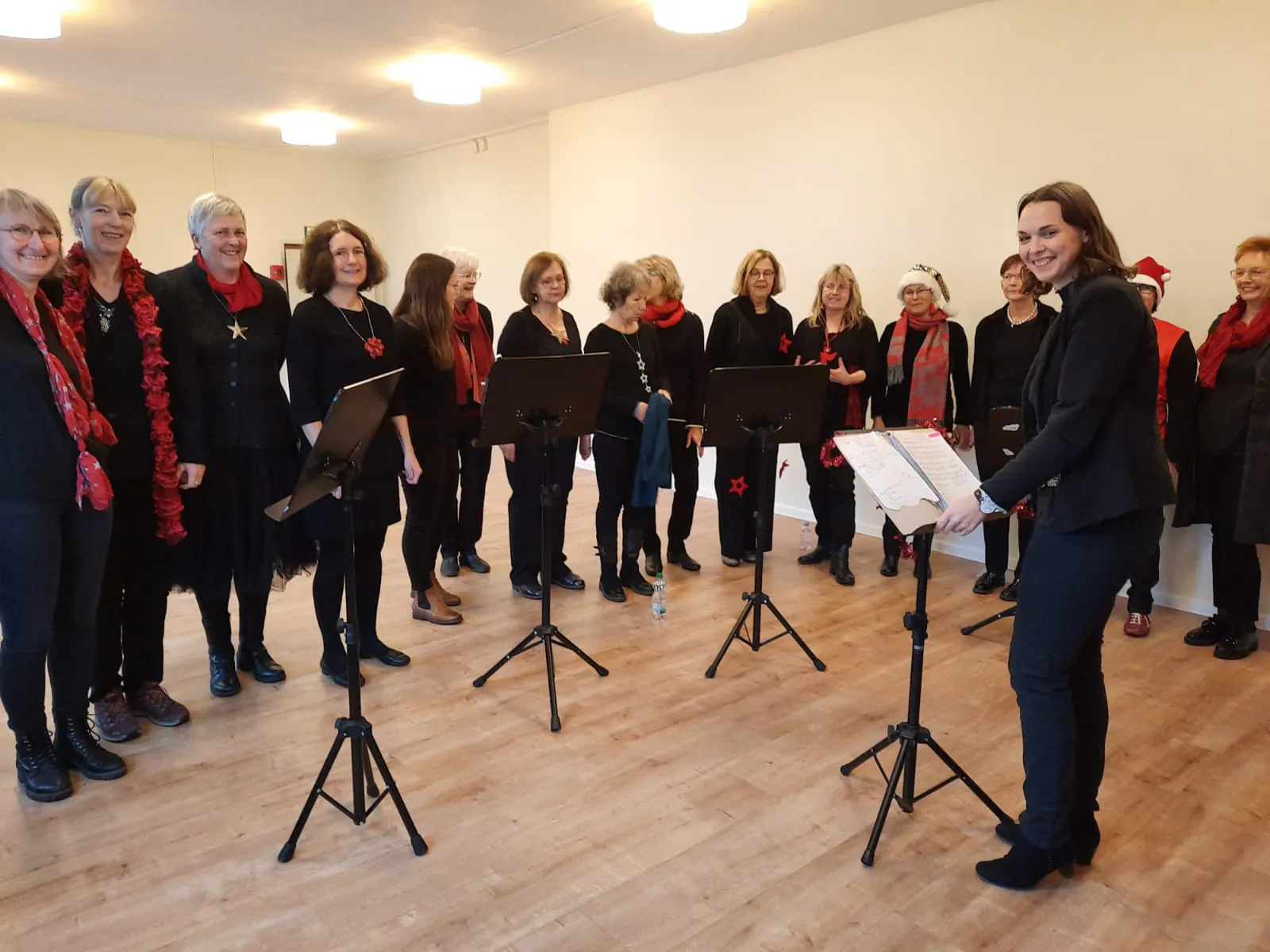 Adventskonzert: der Chor singt vor Notenständern, Anna-Luisa Kächele dirigiert von rechts.
